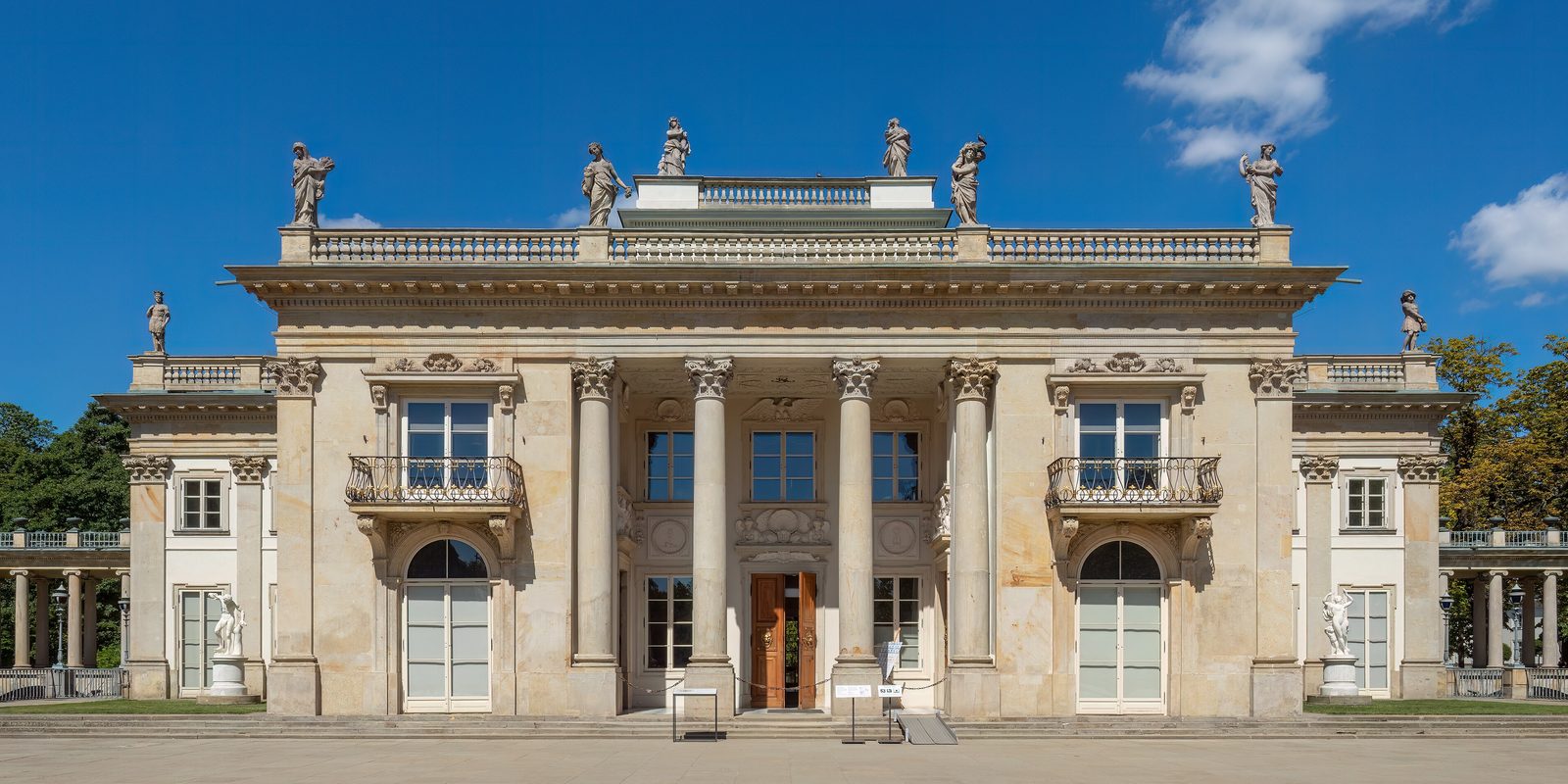 The Palace on the Isle in Warsaw's Łazienki Park, its colonnaded facade under a blue sky