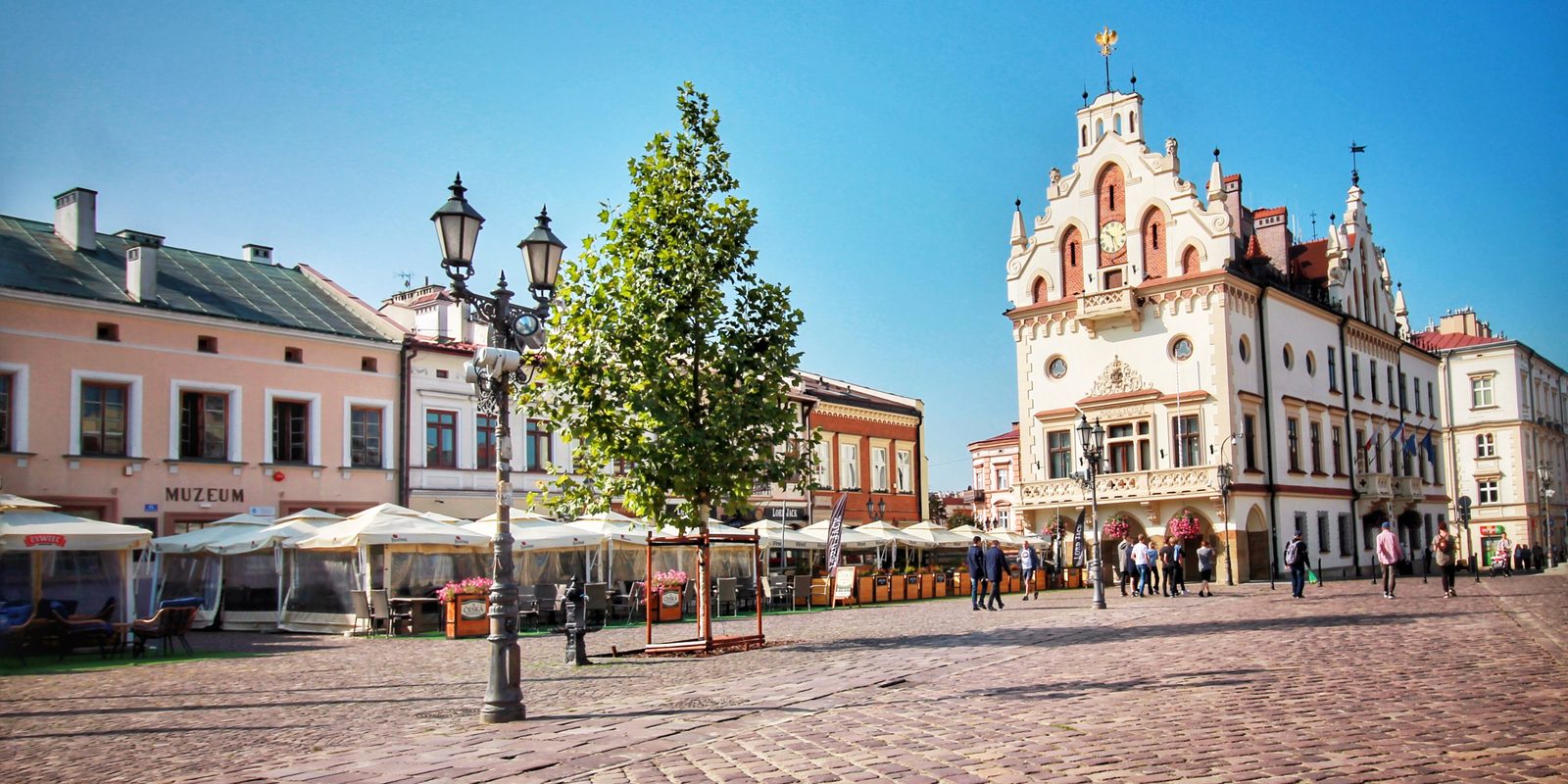 Café awnings on Rzeszów's market square with the red-and-white town hall behind them