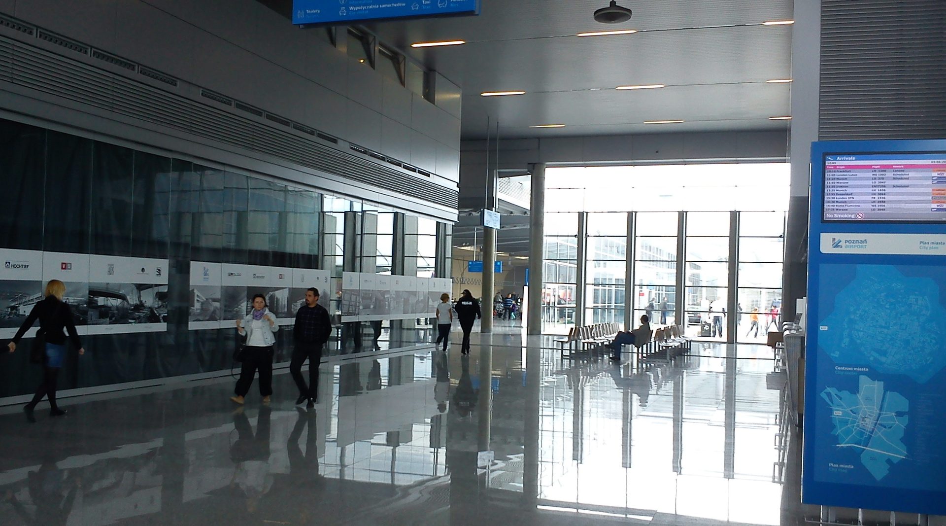 Arrivals area of Poznań-Ławica Airport, with the Poznań Airport city-plan board beside the seating