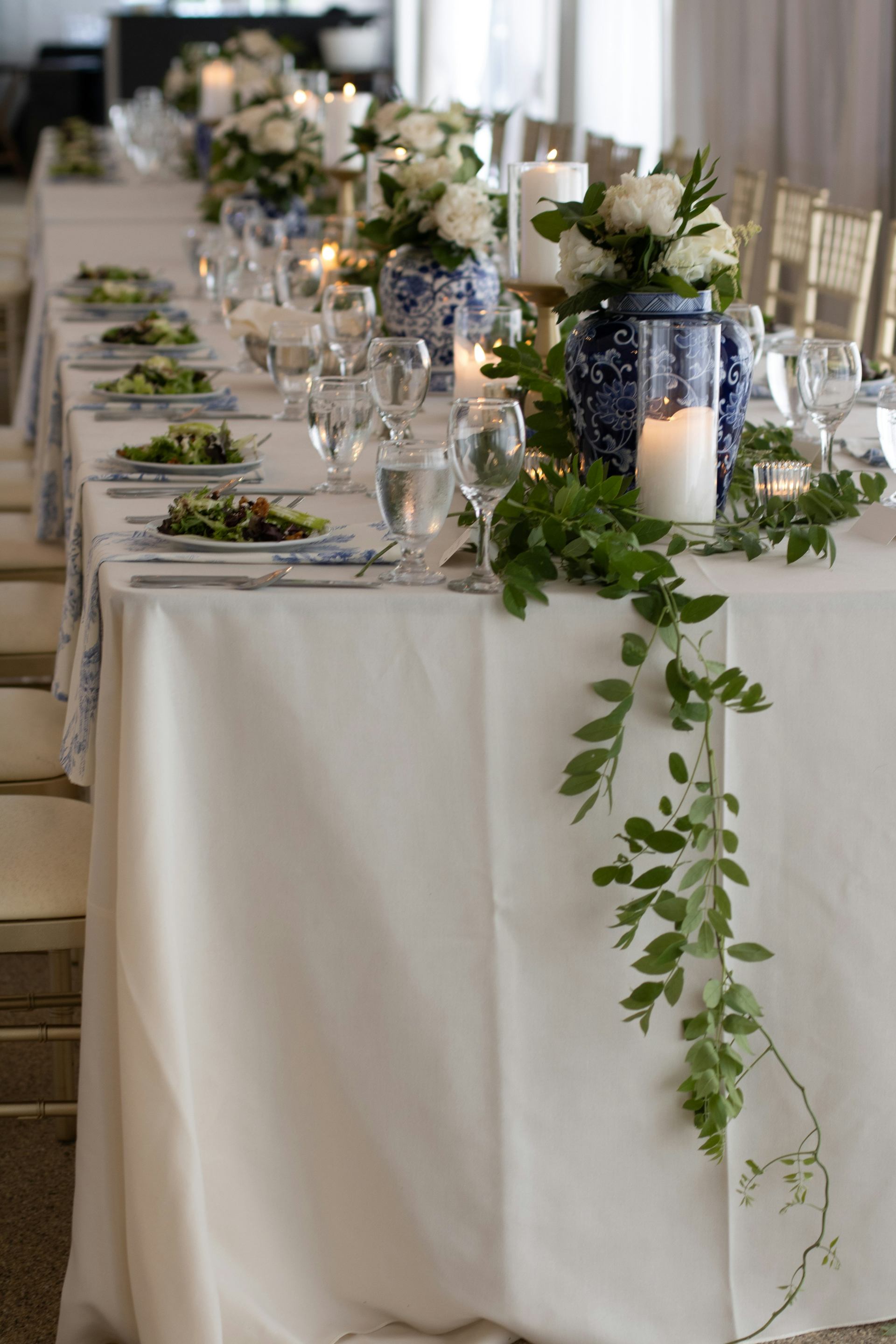 Elegantly set wedding reception table with white flowers, candles, and blue-porcelain centrepiece